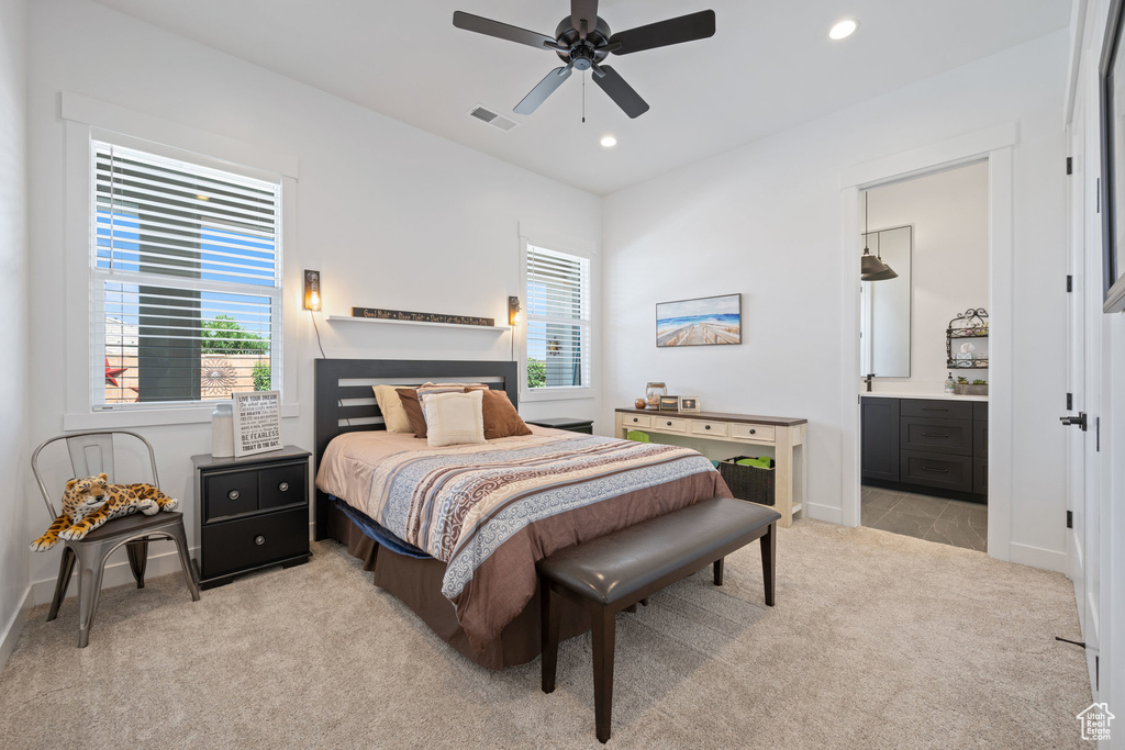 Bedroom featuring light colored carpet, multiple windows, recessed lighting, ensuite bathroom, and a ceiling fan