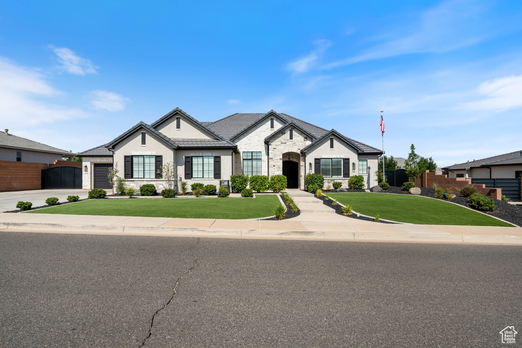 French provincial home featuring stone siding, stucco siding, and an attached garage