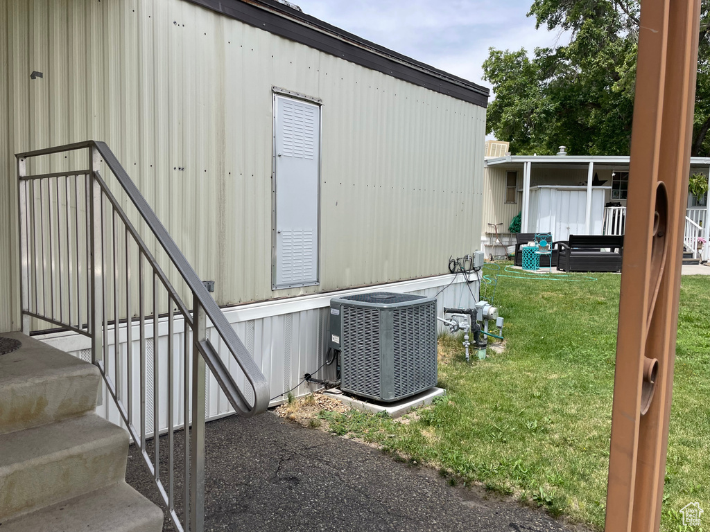 View of side of property featuring a central air condition unit and a lawn