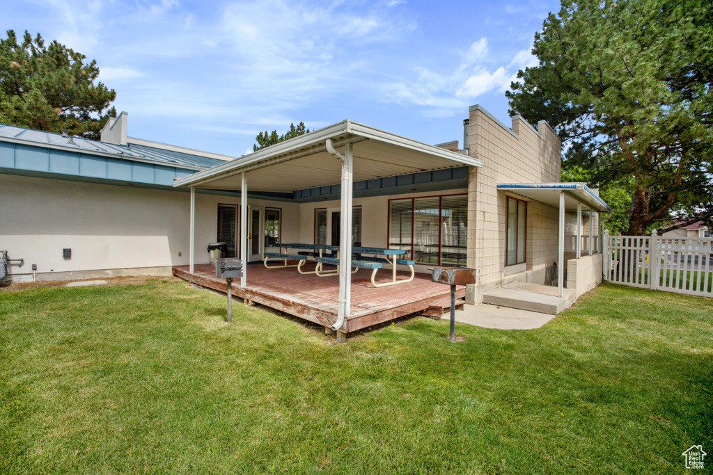 Back of property featuring a chimney, a deck, a standing seam roof, and a metal roof