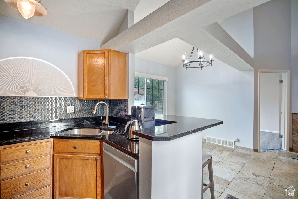 Kitchen with stainless steel dishwasher, vaulted ceiling, decorative backsplash, a peninsula, and a chandelier