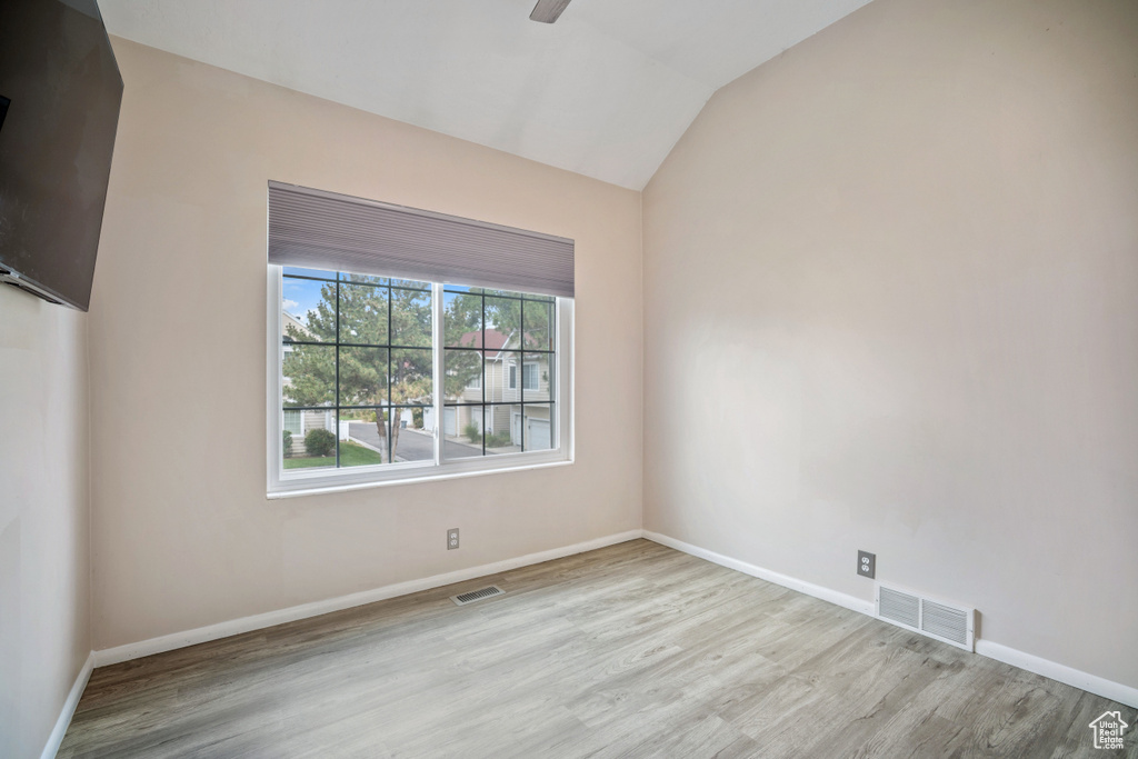 Empty room featuring wood finished floors, vaulted ceiling, and ceiling fan