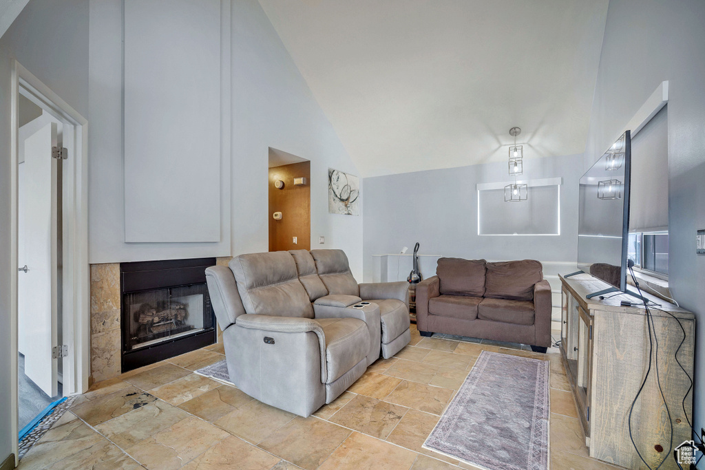 Living area with high vaulted ceiling, a fireplace, and stone tile floors