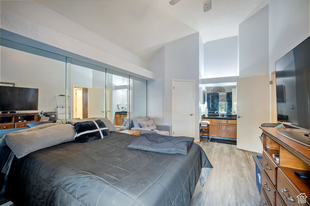 Bedroom with high vaulted ceiling, light wood-type flooring, and ensuite bath