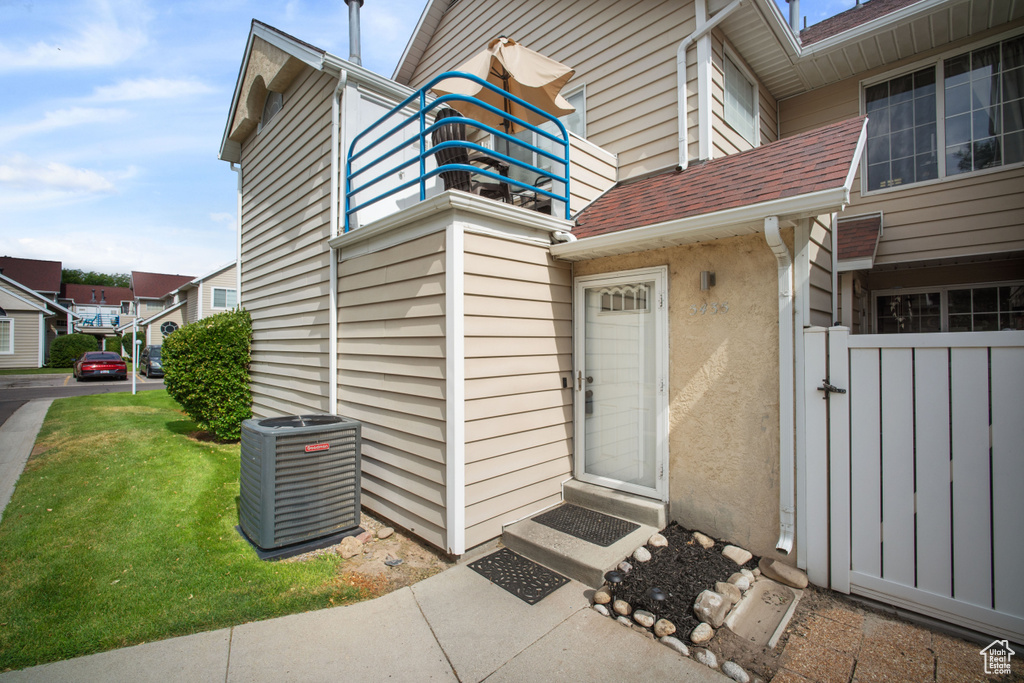 Entrance to property featuring a balcony, stucco siding, roof with shingles, and a gate