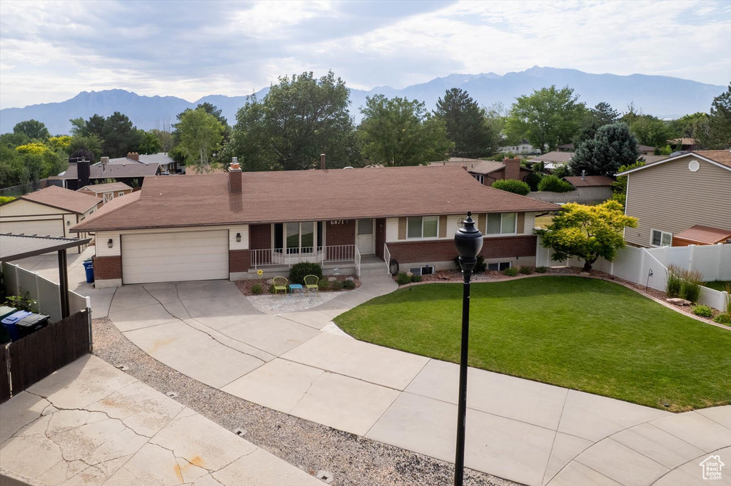 Ranch-style home featuring a porch, driveway, a mountain view, an attached garage, and brick siding