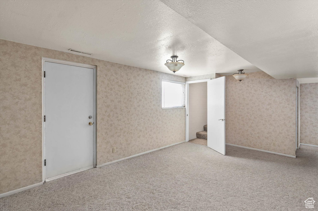 Unfurnished bedroom featuring a textured ceiling, carpet flooring, and wallpapered walls