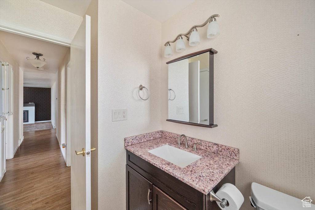 Half bath with wood finished floors and vanity