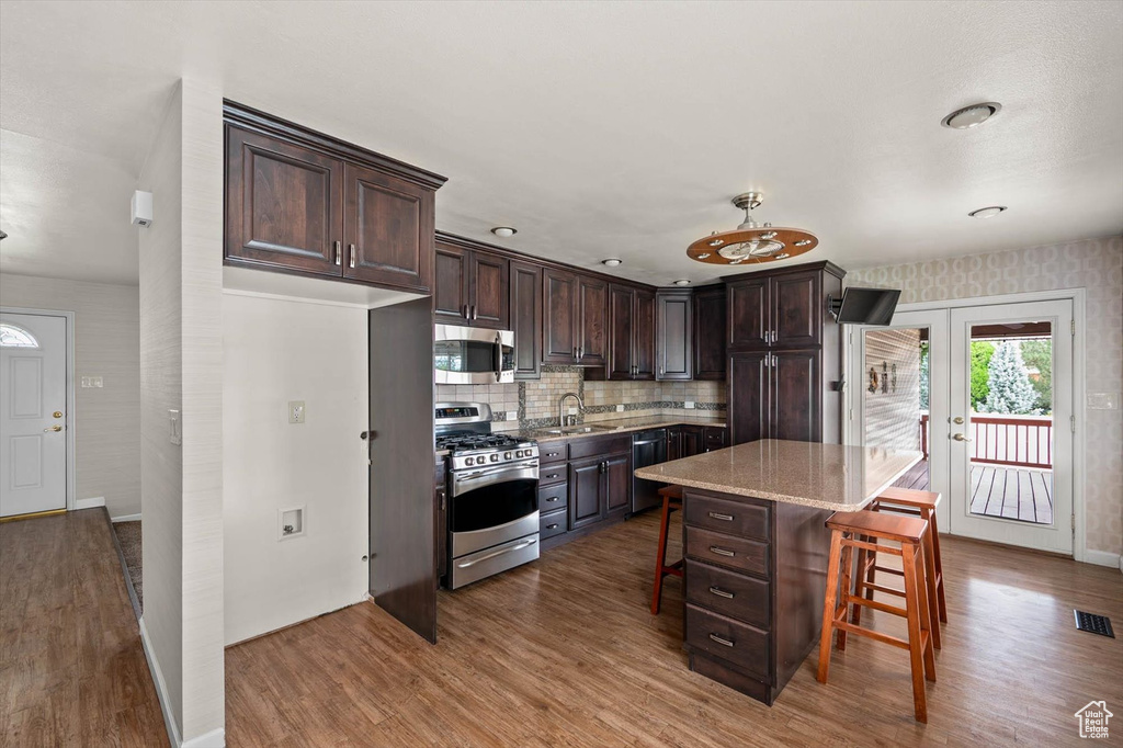 Kitchen featuring stainless steel appliances, wood finished floors, and dark brown cabinets