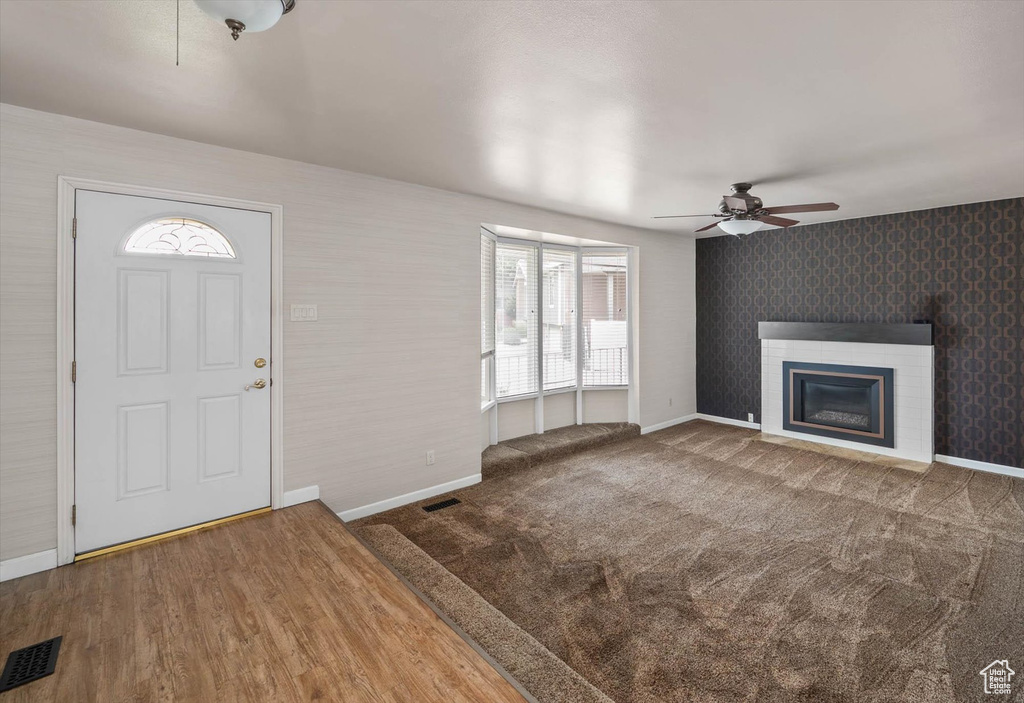 Entrance foyer featuring healthy amount of natural light, ceiling fan, a glass covered fireplace, and wallpapered walls