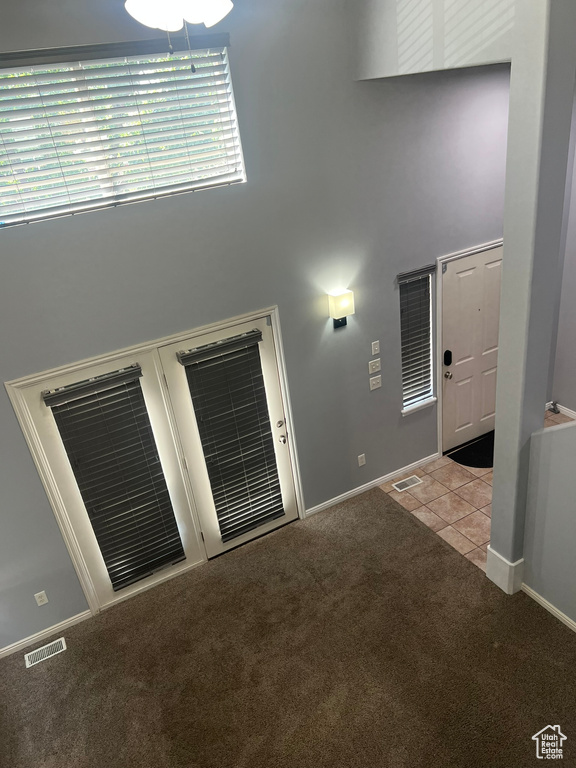 Carpeted empty room featuring a high ceiling and tile patterned floors