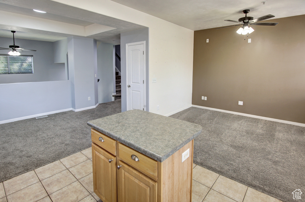 Kitchen with light colored carpet, ceiling fan, open floor plan, and a kitchen island
