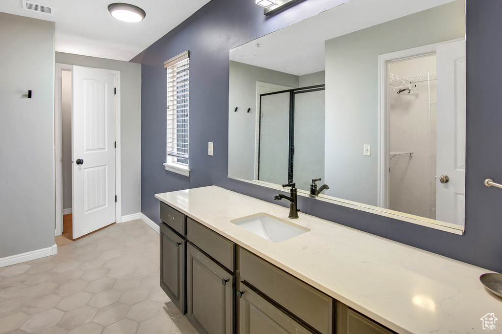 Bathroom featuring vanity, a walk in closet, and a stall shower