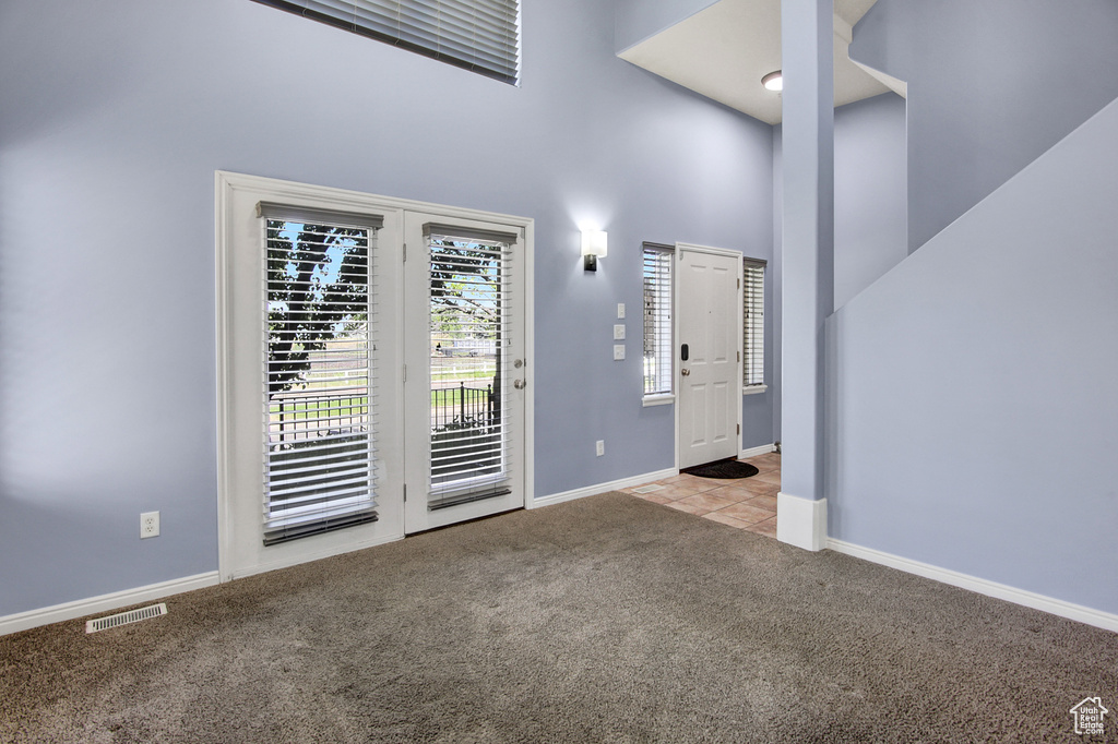 Carpeted spare room with a towering ceiling and baseboards