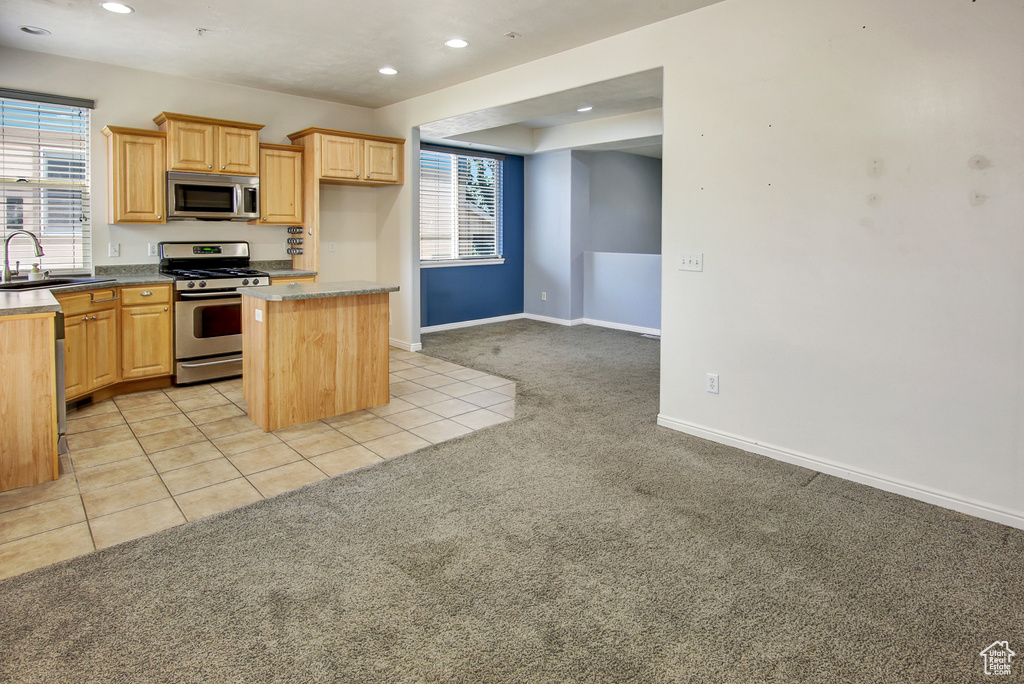 Kitchen featuring stainless steel appliances, light colored carpet, recessed lighting, a kitchen island, and light brown cabinets