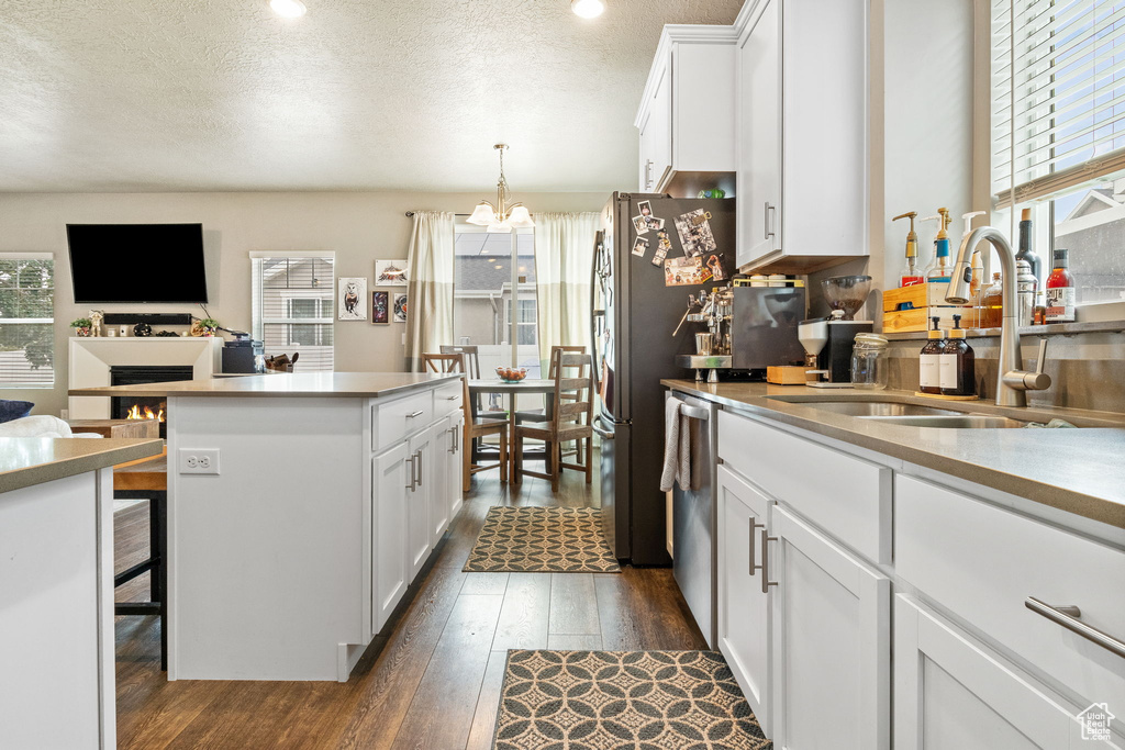 Kitchen featuring dark wood-style flooring, a chandelier, white cabinets, a center island, and a textured ceiling