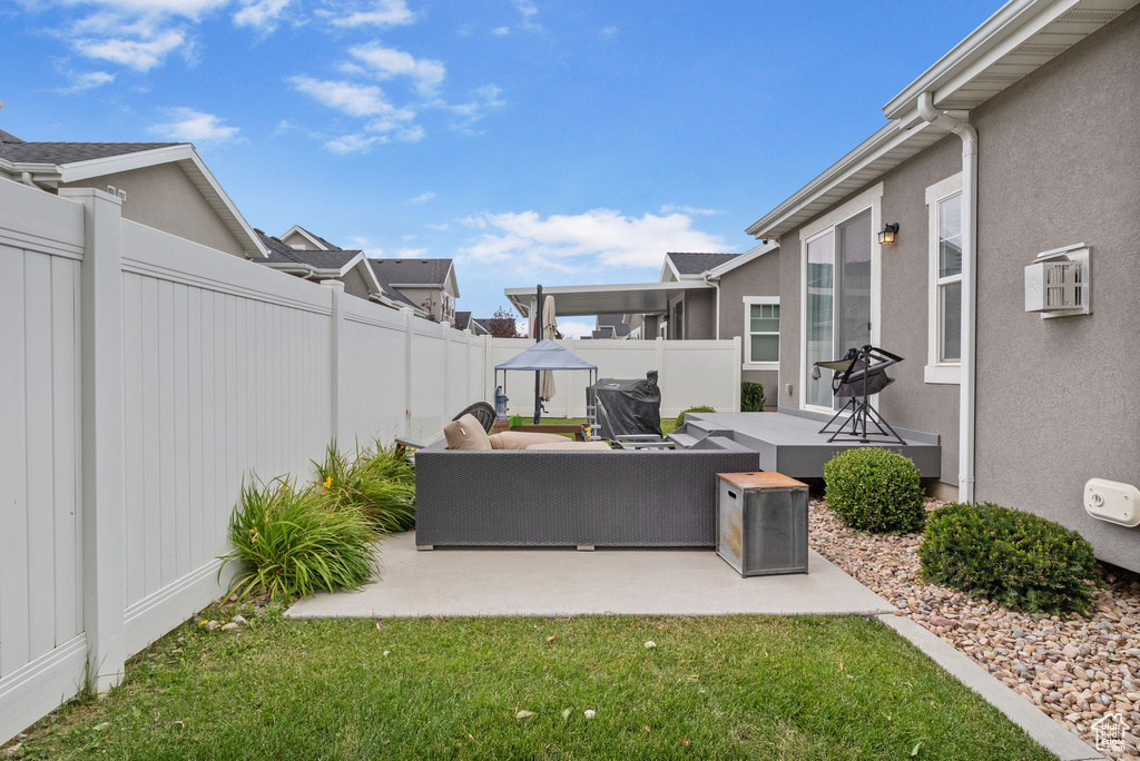 Fenced backyard featuring outdoor lounge area, a patio, a residential view, and an AC wall unit