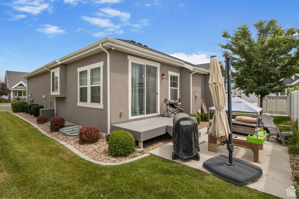 Rear view of house featuring a wooden deck, stucco siding, and a patio area