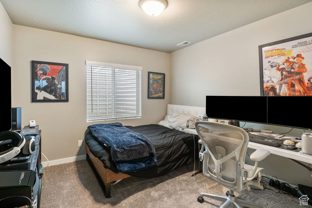 Carpeted bedroom featuring an office area and baseboards