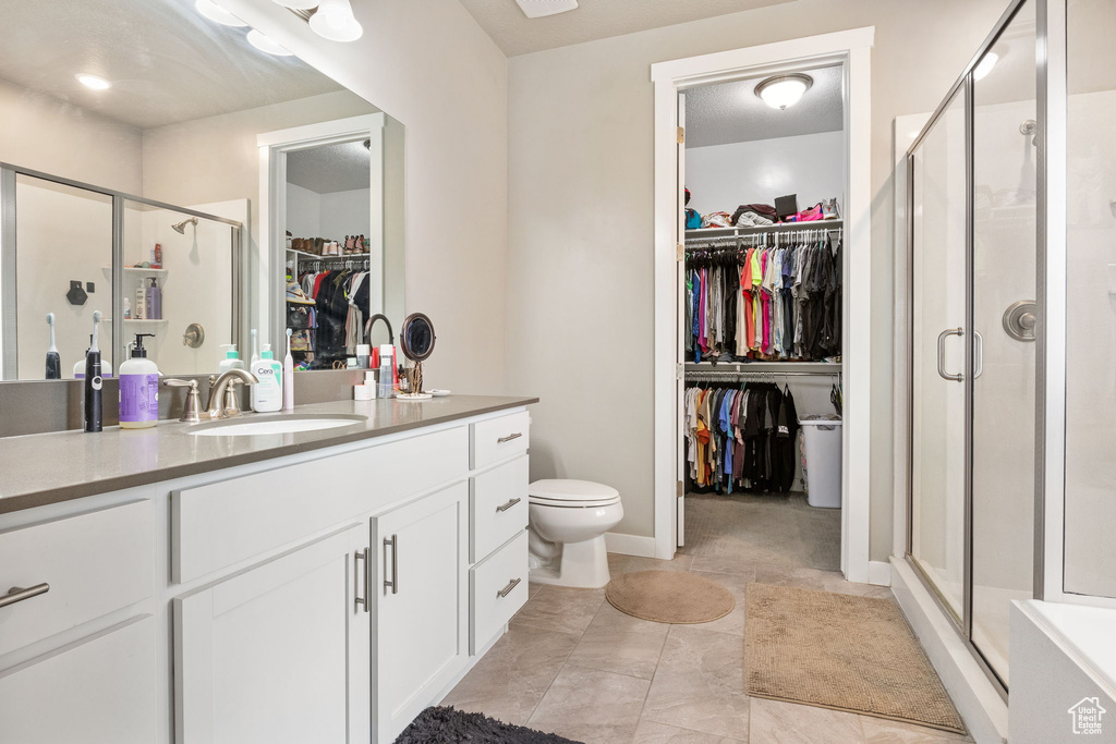 Full bathroom featuring vanity, a spacious closet, and a shower stall