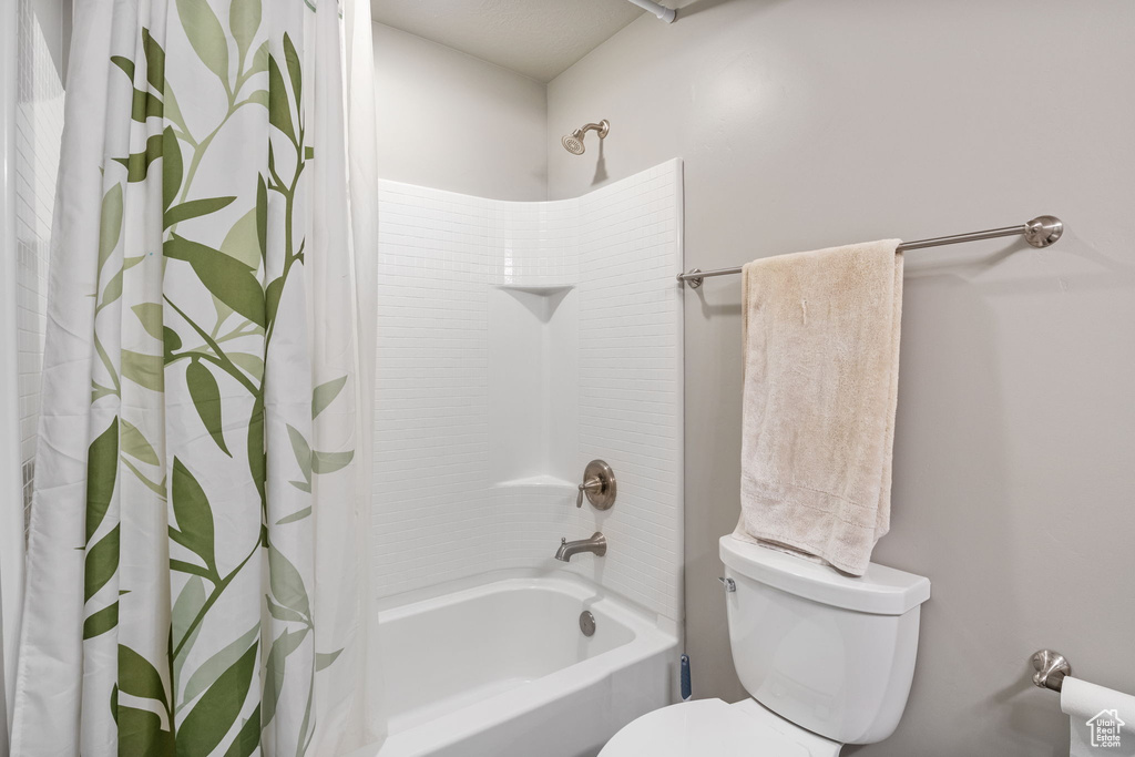 Bathroom featuring shower / bathtub combination with curtain and toilet
