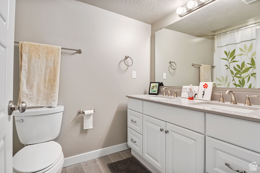 Bathroom with double vanity, wood finish floors, and a textured ceiling