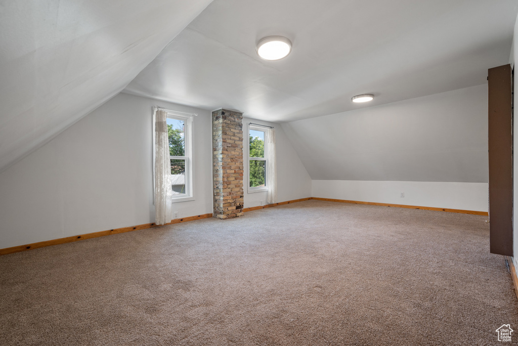 Additional living space with vaulted ceiling and carpet