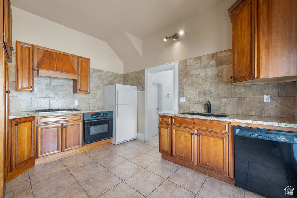 Kitchen with black appliances, premium range hood, brown cabinets, and vaulted ceiling
