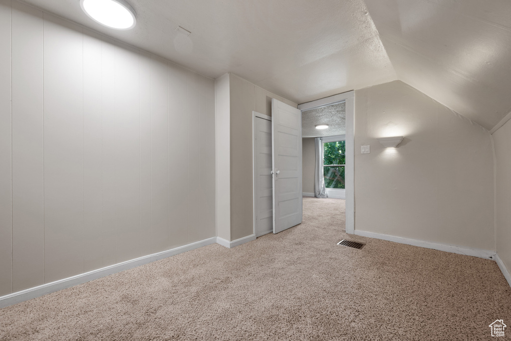 Additional living space featuring light colored carpet and lofted ceiling