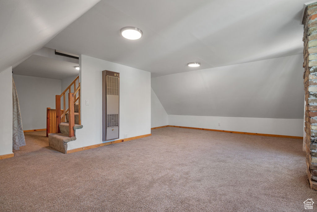 Bonus room with a heating unit, carpet floors, lofted ceiling, and stairway