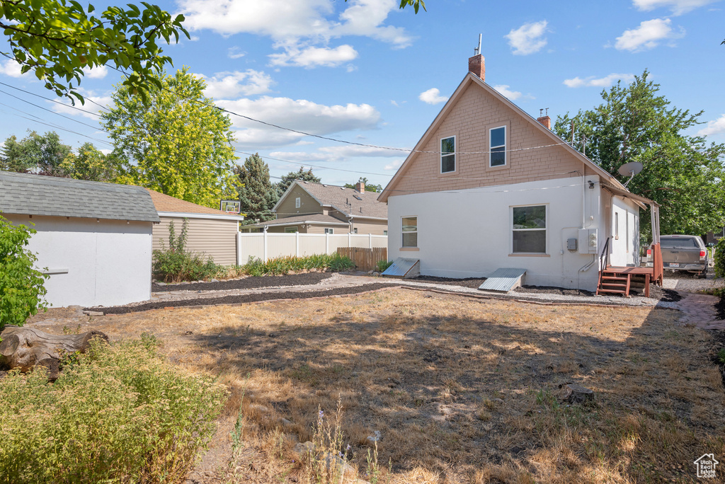 Rear view of property featuring a chimney and a storage shed