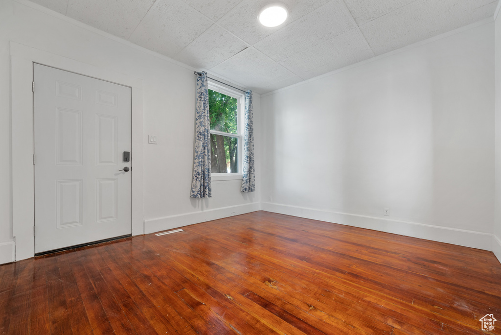 Foyer entrance with crown molding and wood-type flooring