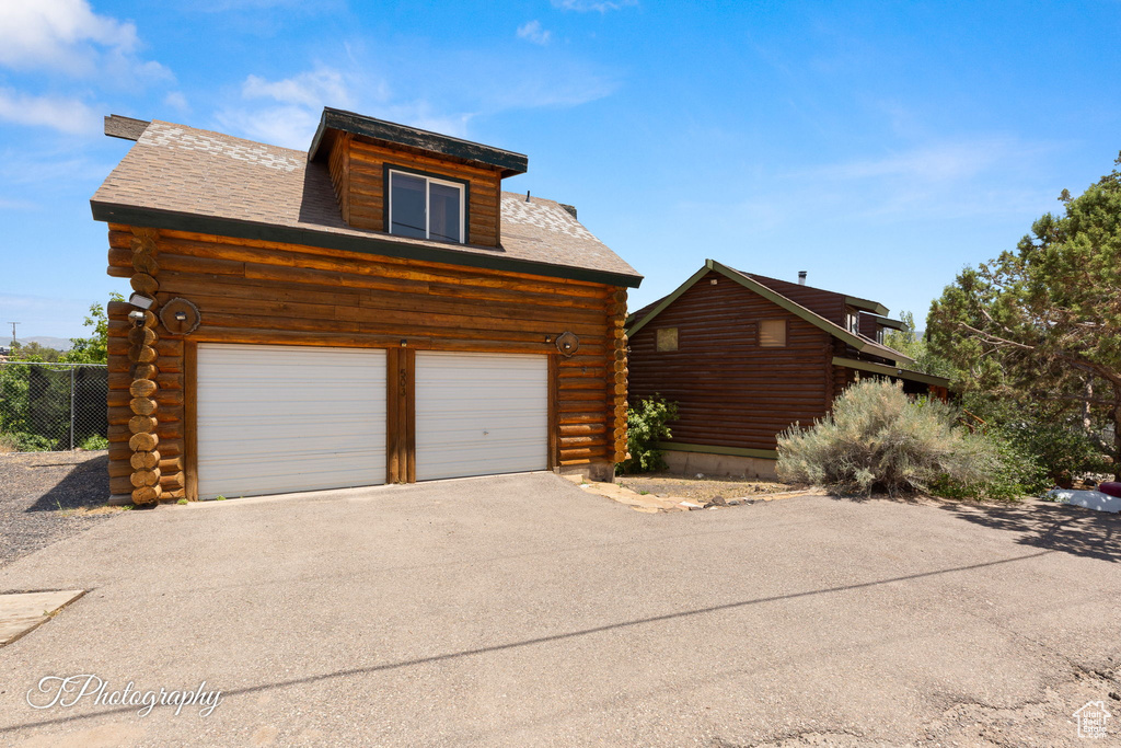 View of property exterior with log siding and driveway