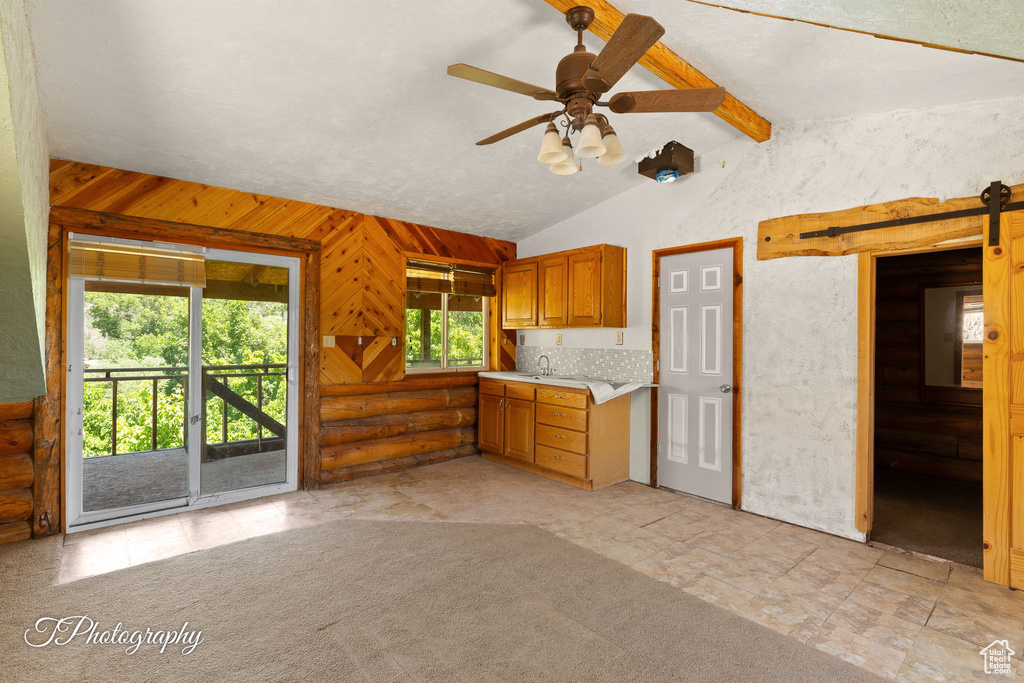 Kitchen with light countertops, ceiling fan, brown cabinets, and rustic walls