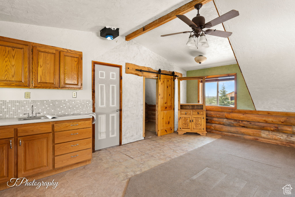 Kitchen featuring a barn door, brown cabinetry, light countertops, and ceiling fan