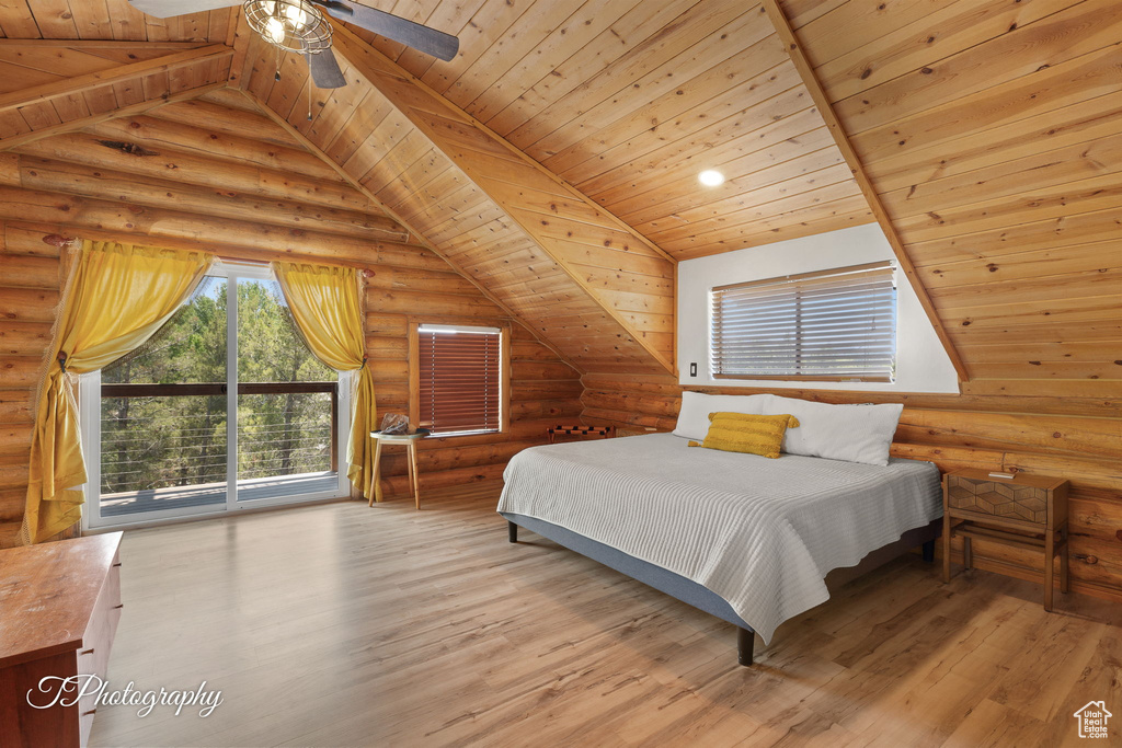 Bedroom with rustic walls, wooden ceiling, wood finished floors, and access to outside