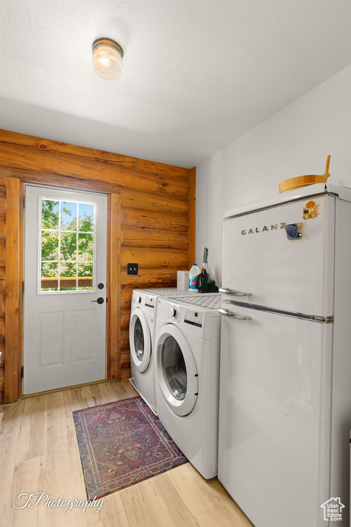 Laundry area featuring log walls, independent washer and dryer, and light wood-style flooring