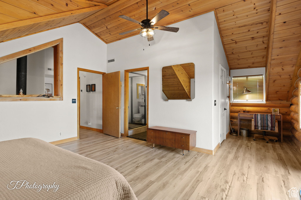 Bedroom with vaulted ceiling, wooden ceiling, wood finished floors, log walls, and connected bathroom