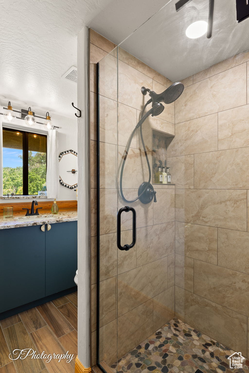 Full bathroom with a stall shower, vanity, and wood tiled floors