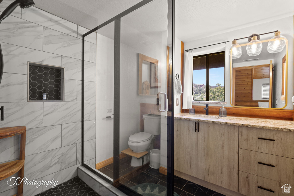 Bathroom with a stall shower, vanity, and marble look tiles