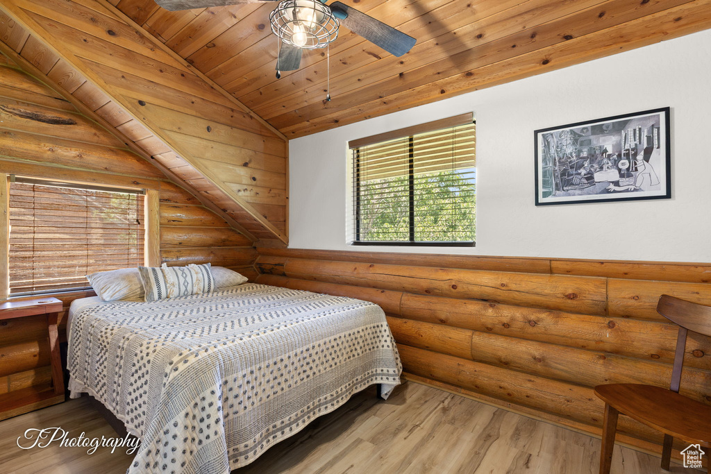 Bedroom featuring rustic walls, multiple windows, wood ceiling, lofted ceiling, and wood finished floors