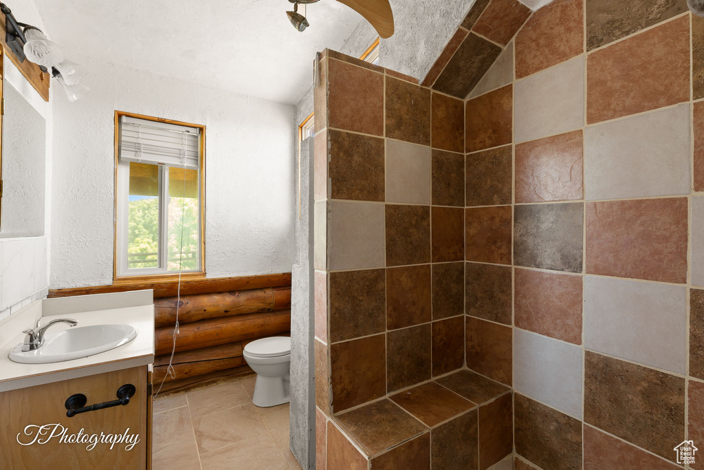 Full bathroom featuring vanity, a textured wall, and a tile shower