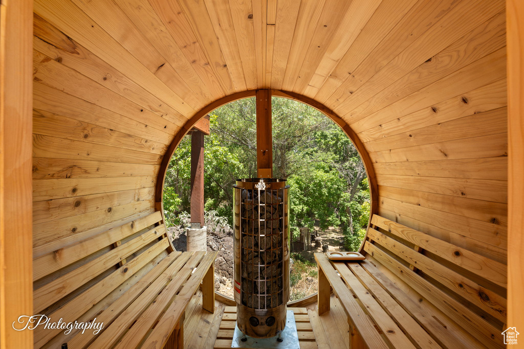 Relaxing sauna featuring wooden walls, wood ceiling, and wood-type flooring