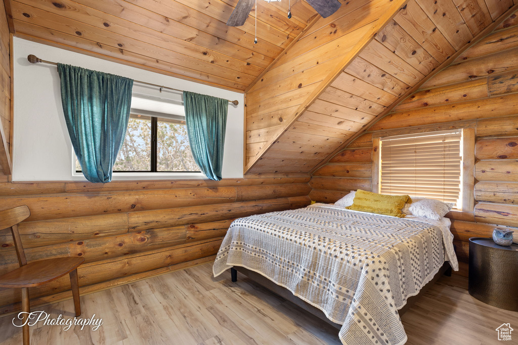 Bedroom with rustic walls, wood finished floors, lofted ceiling, and wood ceiling