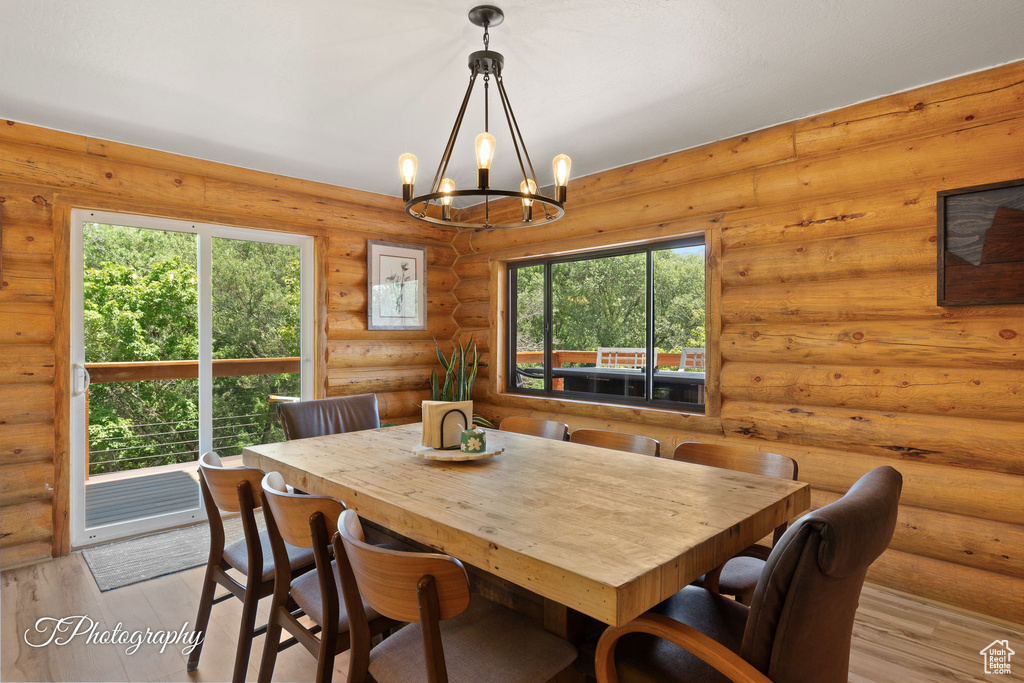 Dining room with a chandelier, light wood-style floors, and rustic walls
