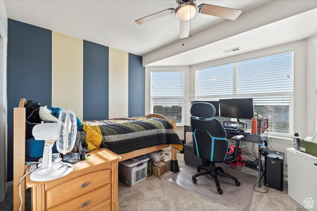 Carpeted bedroom with a desk and ceiling fan