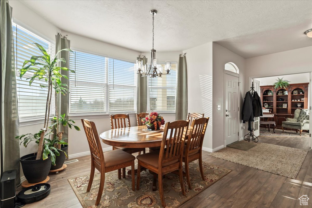 Dining space featuring a chandelier, wood finished floors, and a textured ceiling