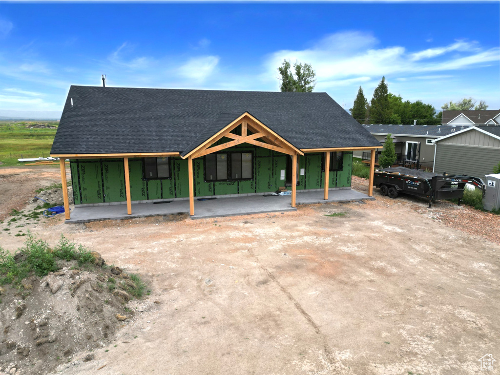 View of front of house with a shingled roof and covered porch