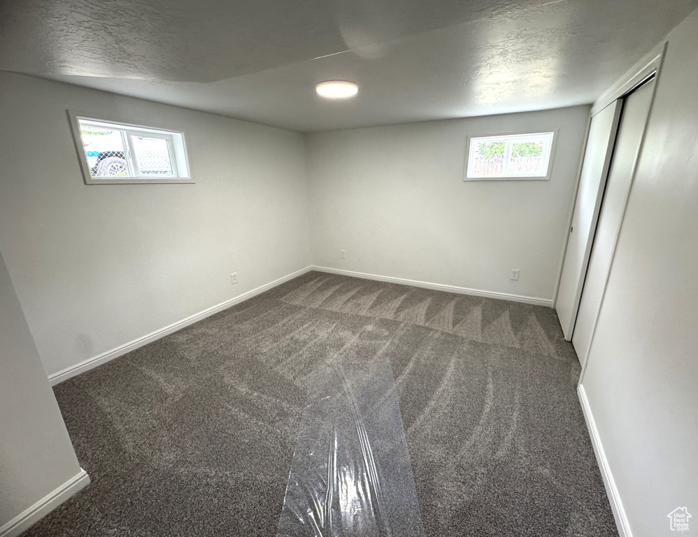 Basement featuring dark colored carpet and a textured ceiling