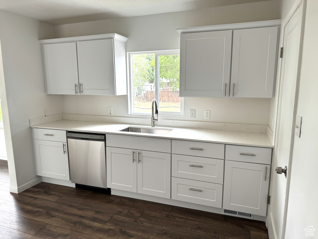 Kitchen featuring stainless steel dishwasher, dark wood-style flooring, light countertops, and white cabinetry